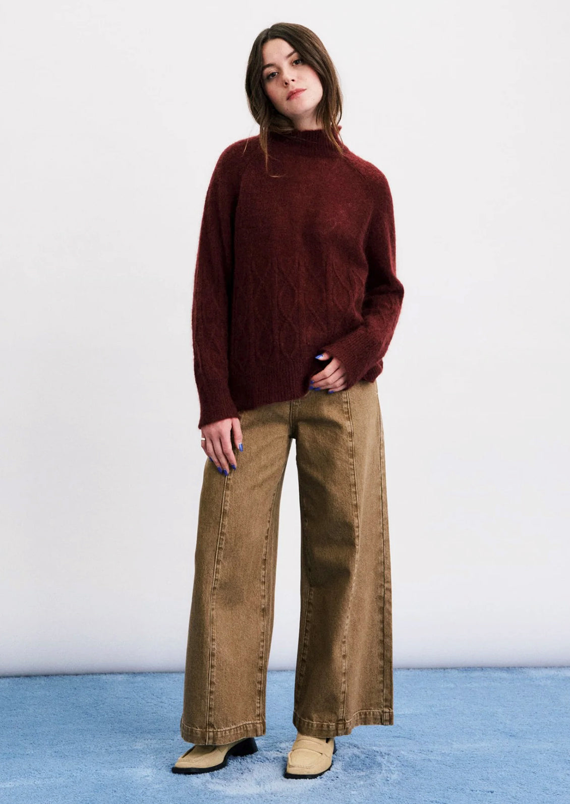 A person wearing a maroon mohair blend sweater with cable stitching detail on lower half.