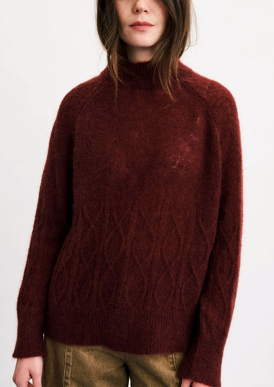 A person wearing a maroon mohair blend sweater with cable stitching detail on lower half.