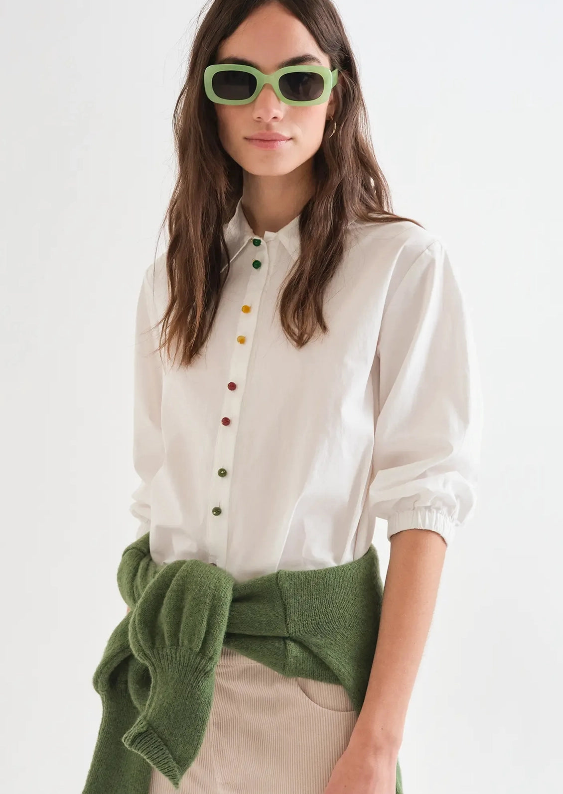 A person wearing a white shirt with multicolor beaded buttons.
