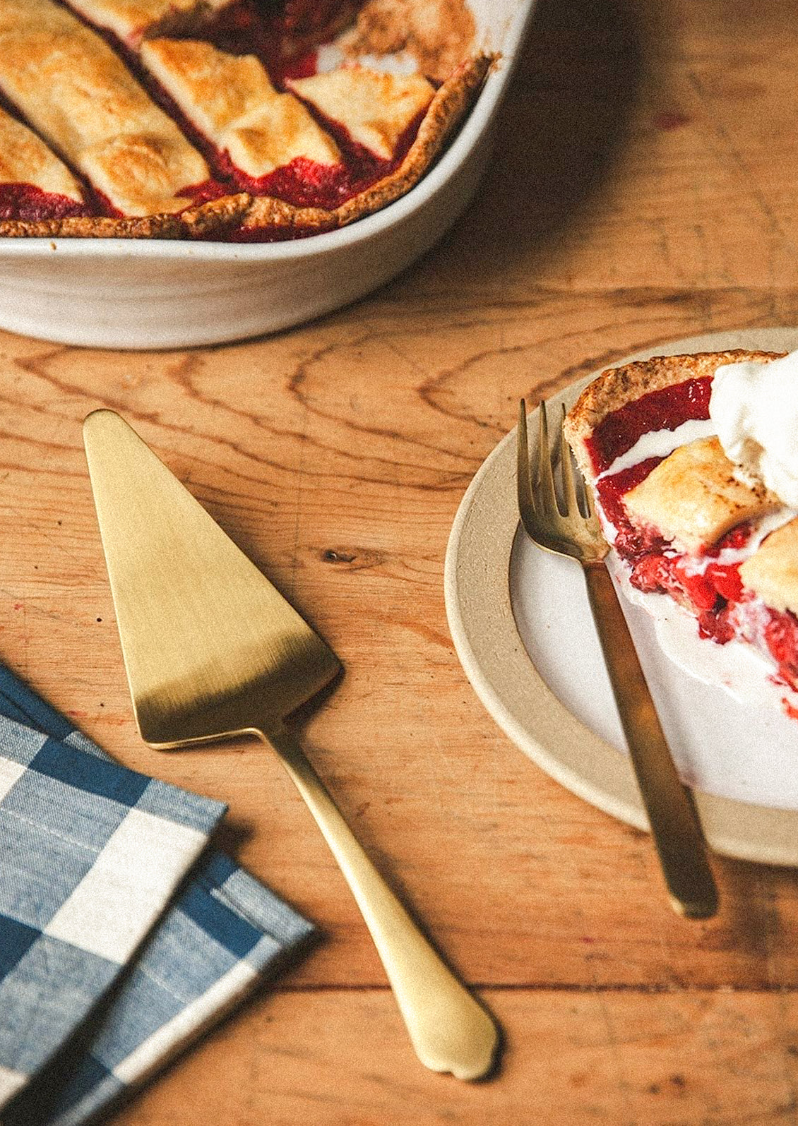 A stainless steel cake server in gold on a table next to pie.