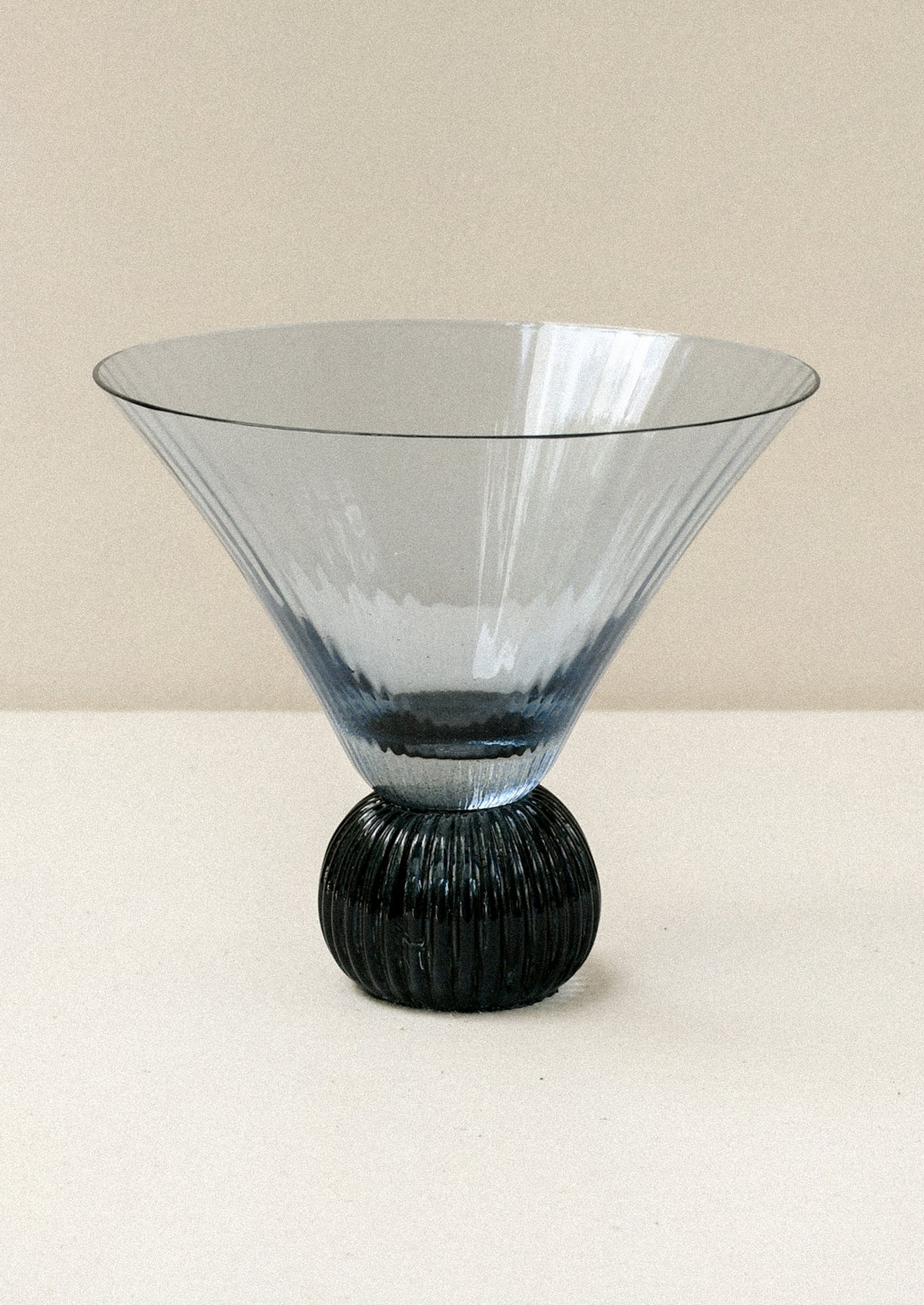 A short blue glass martini glass with ribbed, flared shape.