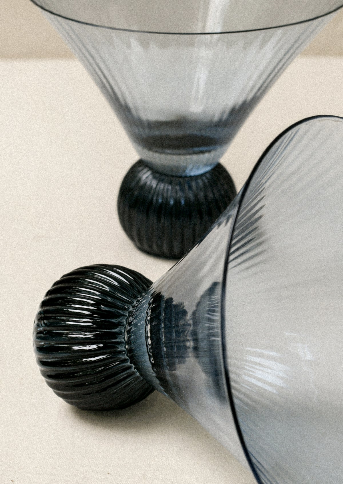 Two short blue glass martini glasses with ribbed, flared shape.