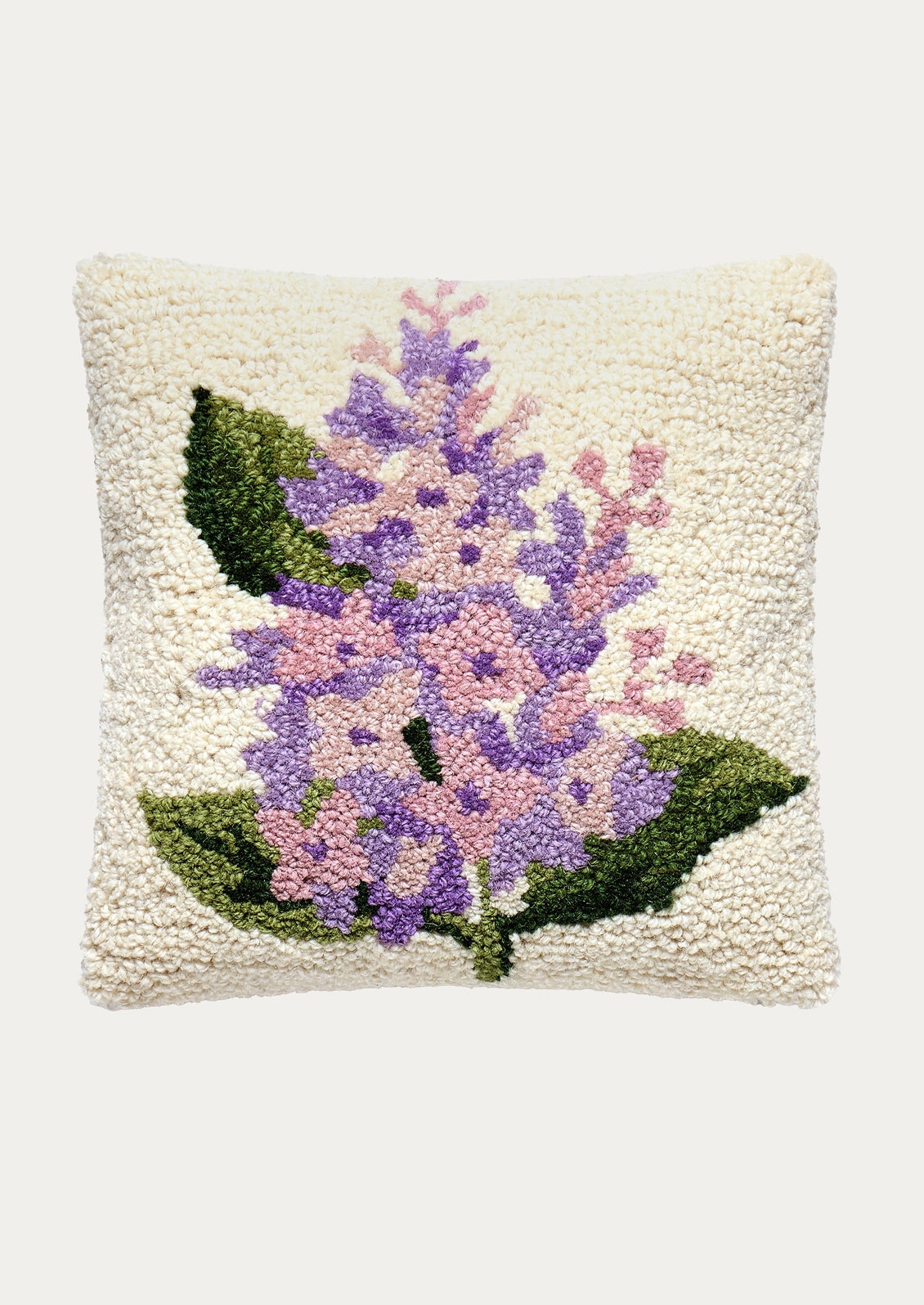 A wool hook pillow in ivory with lilac imagery.