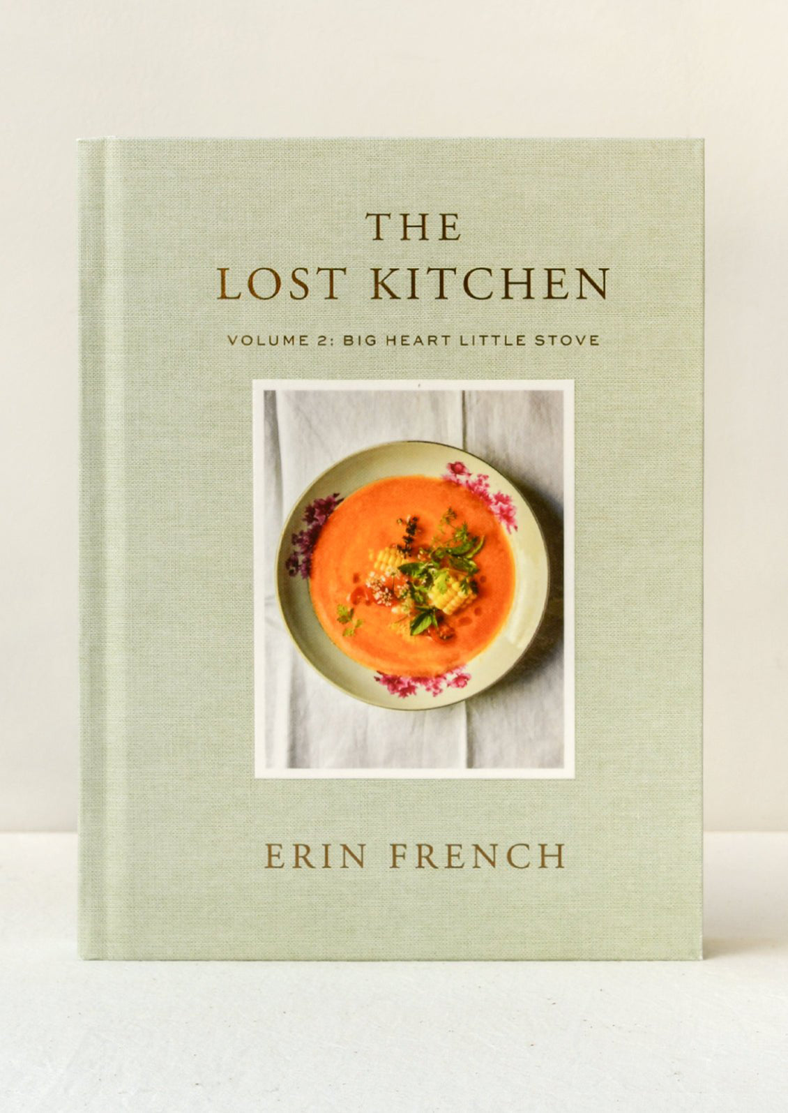 A book titled "The Lost Kitchen Volume 2: Big Heart Little Stove" by Erin French standing upright on a table.