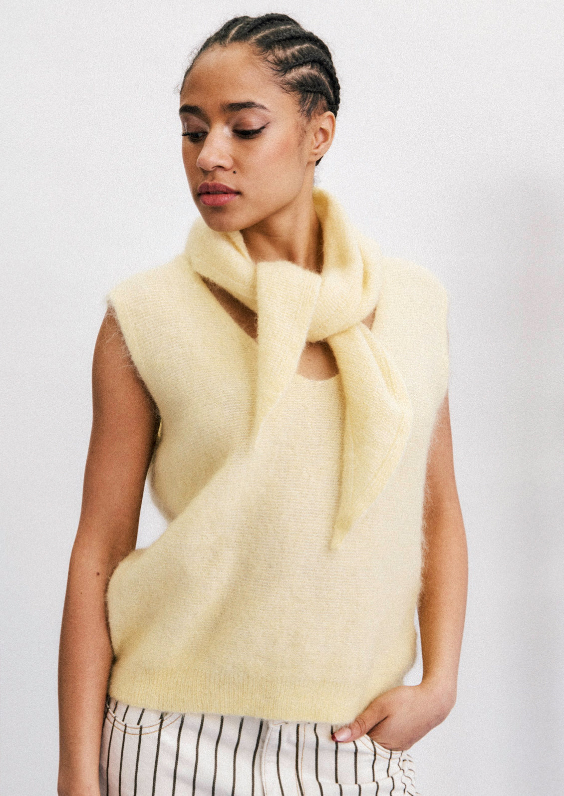 A woman wearing a mohair blend scarf and top in a canary yellow color.