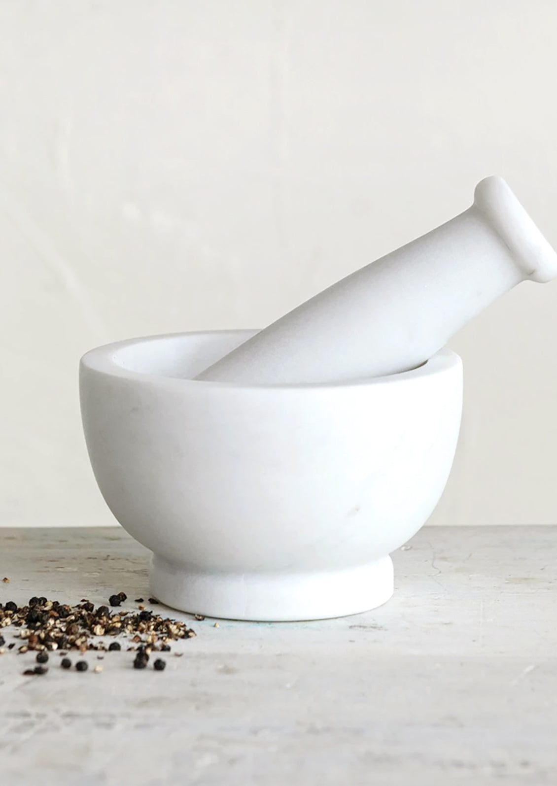 A mortar and pestle in solid white marble.