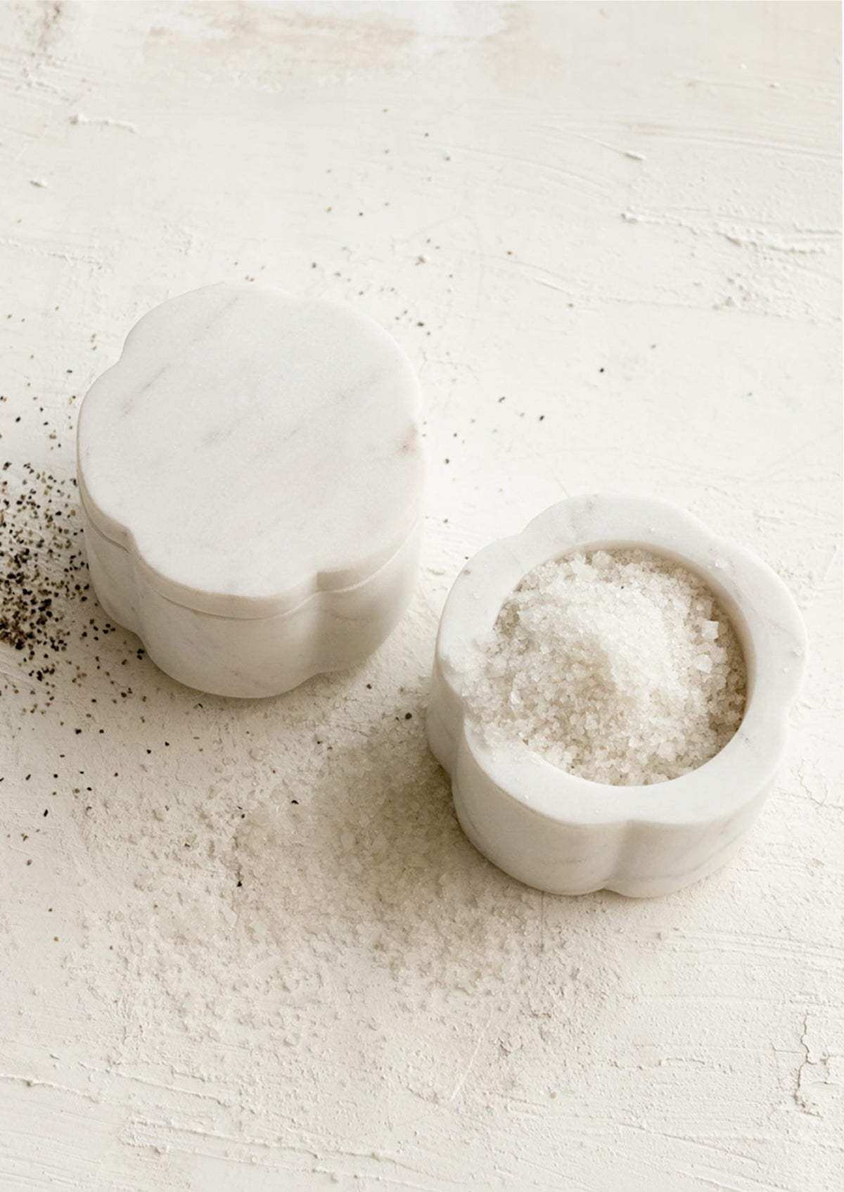 A stacked set of flower-shaped marble pinch pots holding salt and pepper.
