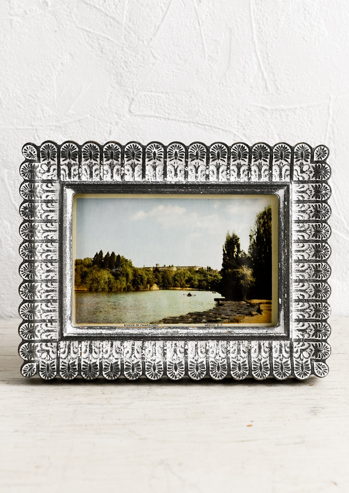 A picture frame with scalloped edges in dark grey with white paint wash.
