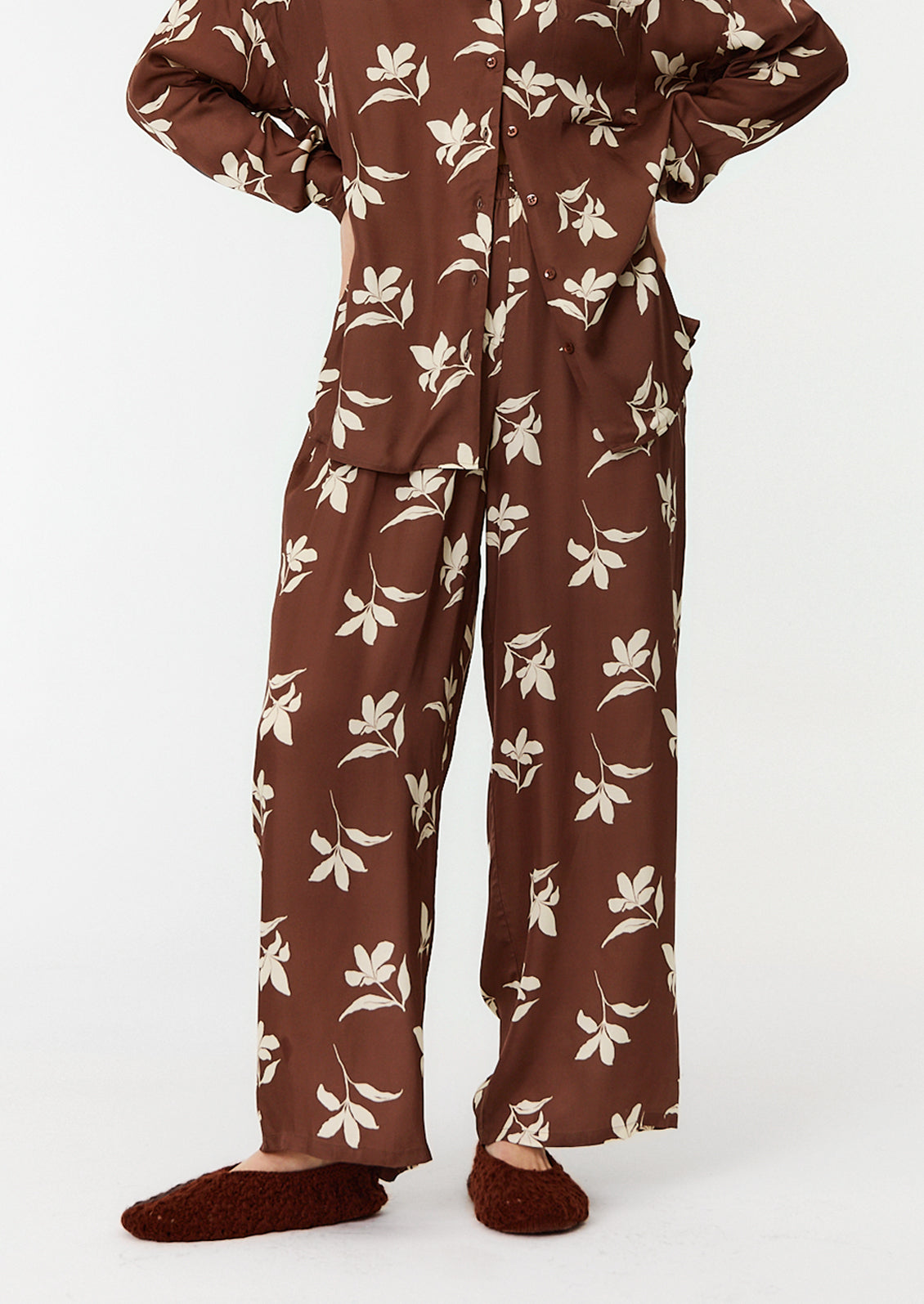 A person wearing a matching set of brown and white floral pajama style clothes.