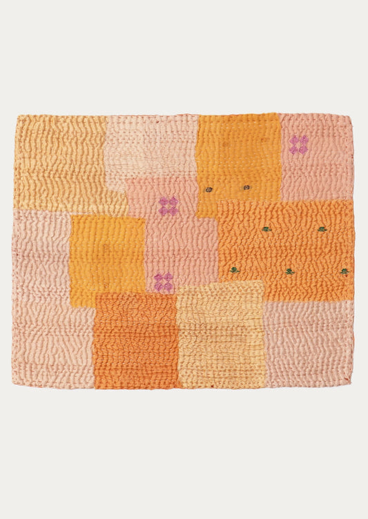 A patchwork placemat made from recycled vintage saris, in pink and orange color palette.