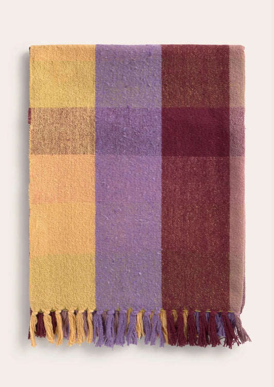 Plaid blanket with purple, yellow, and red colors on a white background
