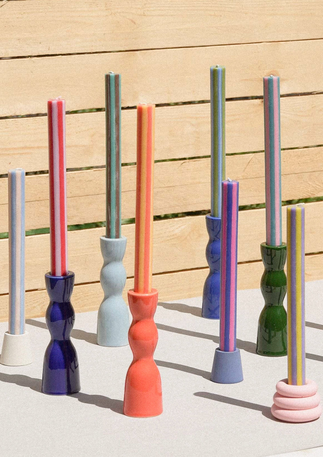 Multicolor striped taper candles in ceramic taper holders.