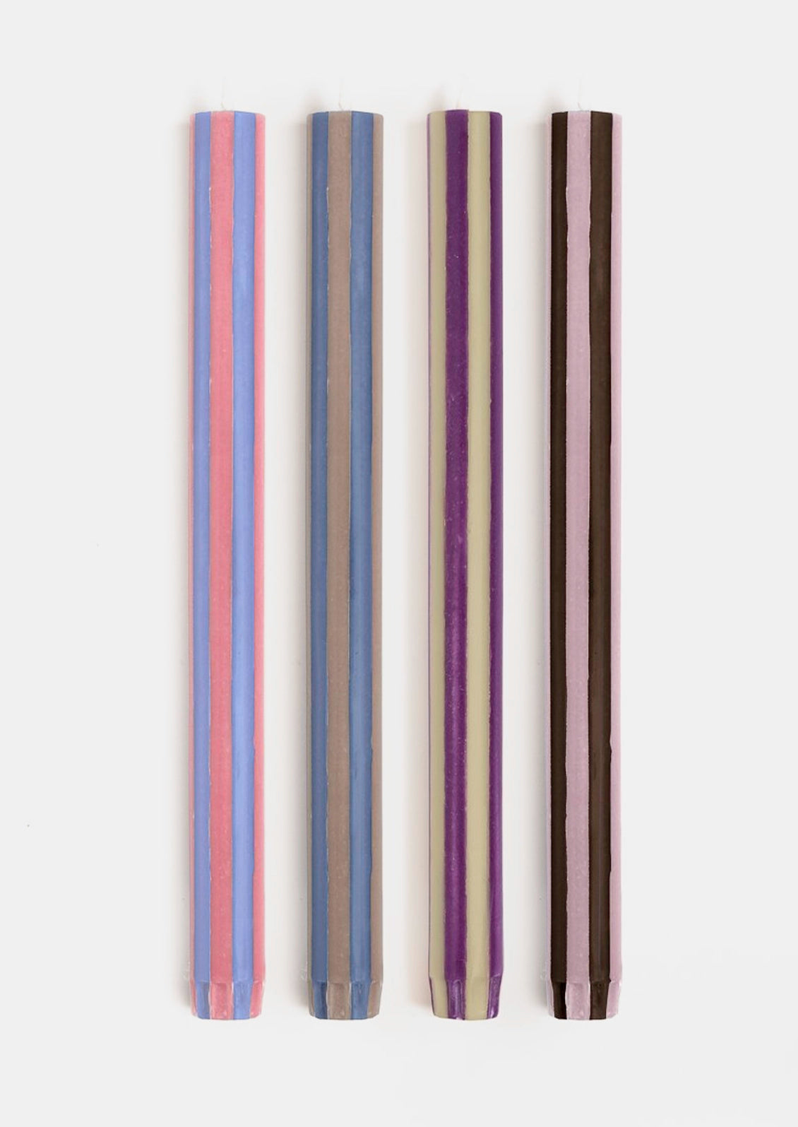 A set of striped taper candles in varying purple, blue, brown, and pink hues.