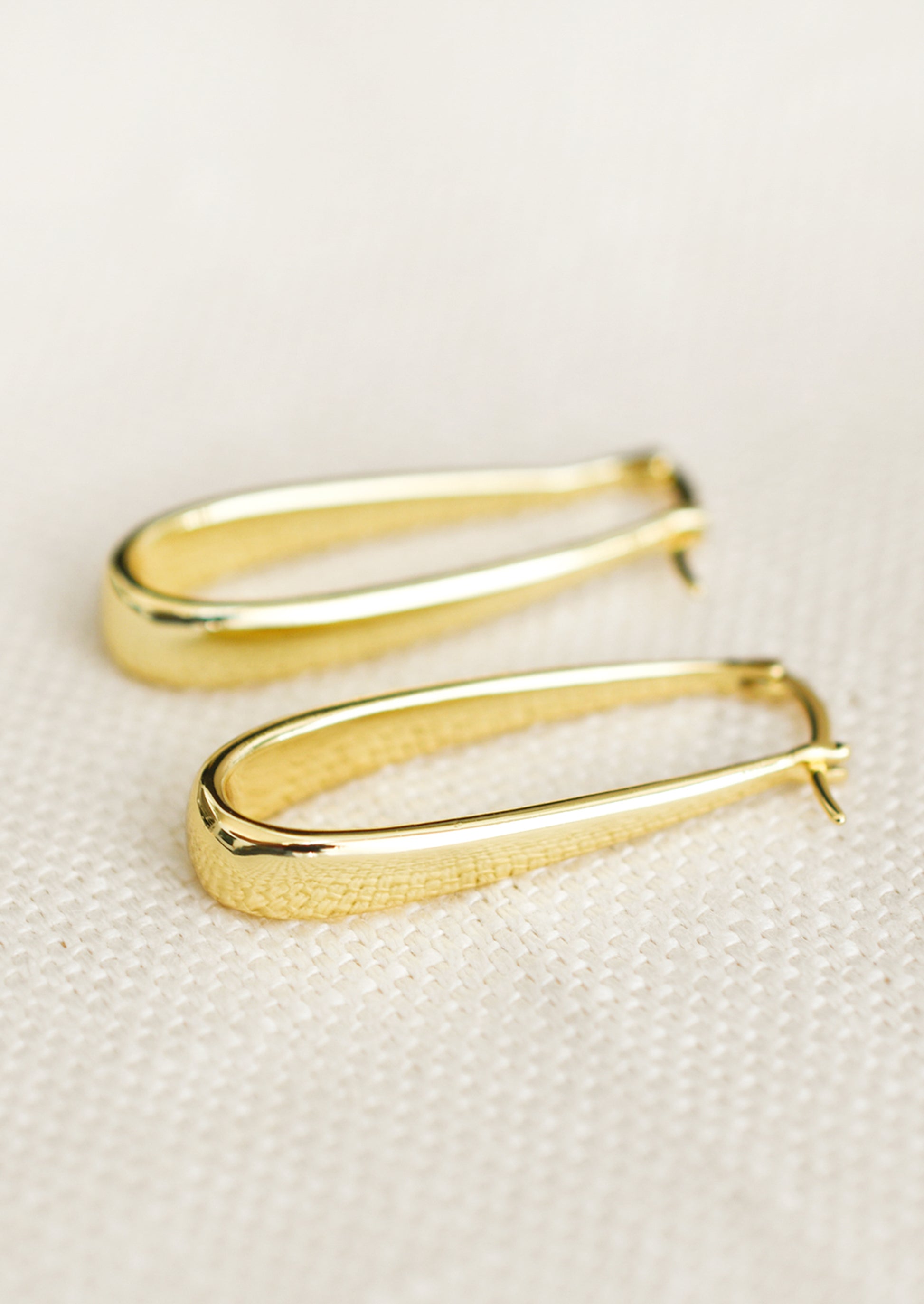 A pair of oblong hoop earrings with subtly tapered thickness, in gold.