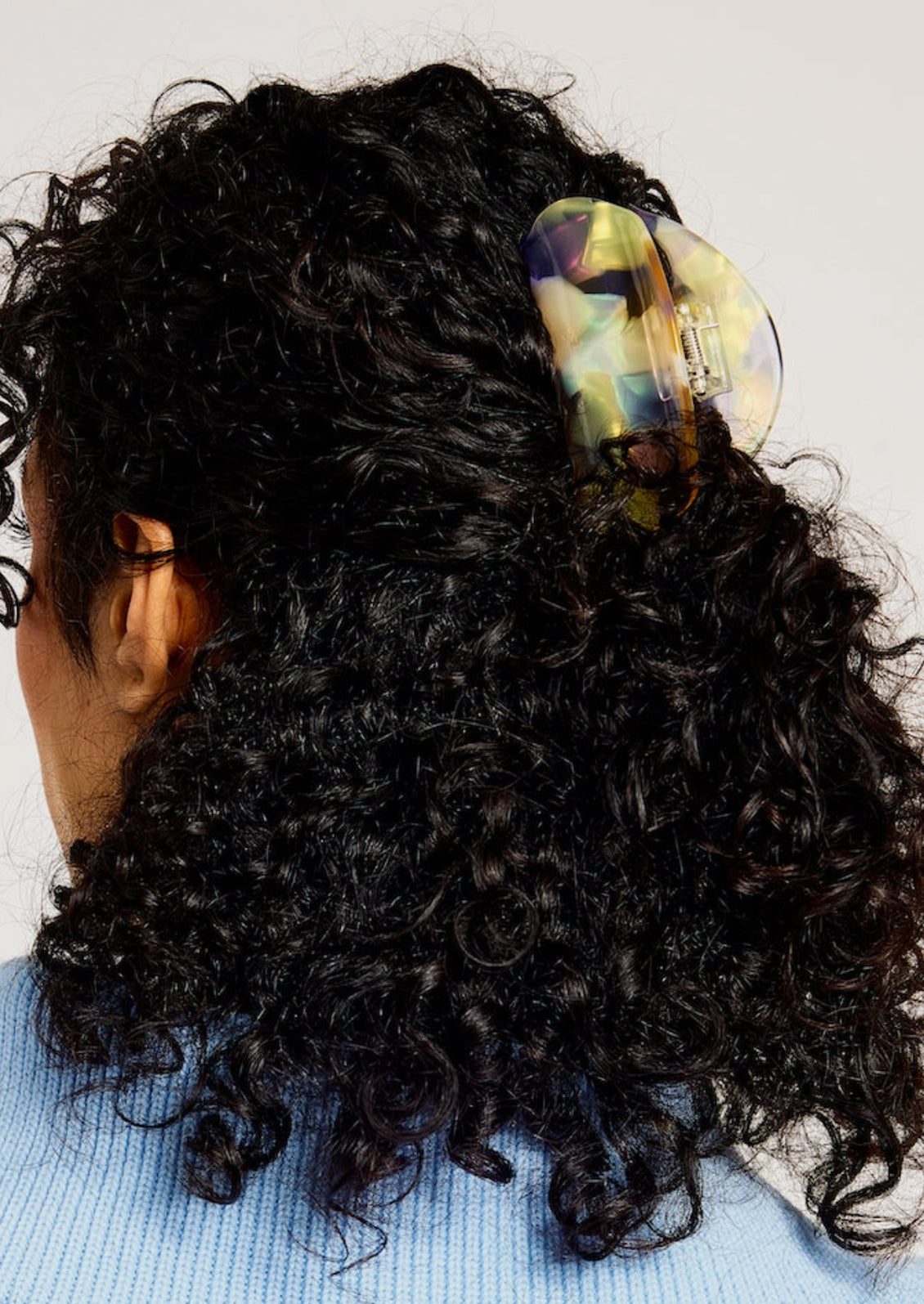 A woman wearing a hair claw with an iridescent opal design.