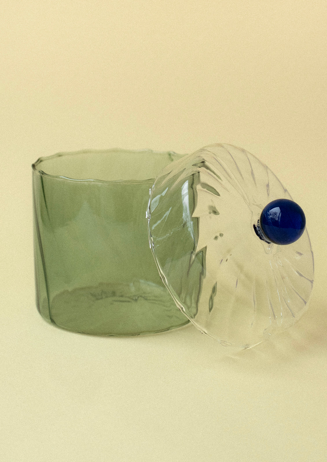 A green tinted glass jar with blue knob on lid.