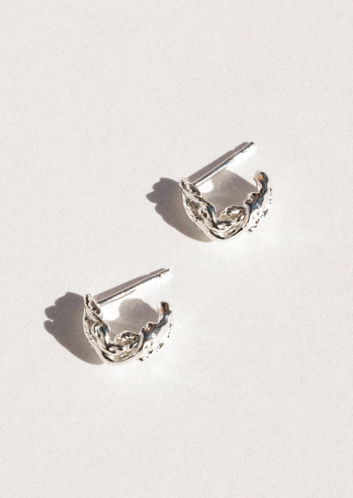 A pair of sterling silver earrings in an abstract shape.