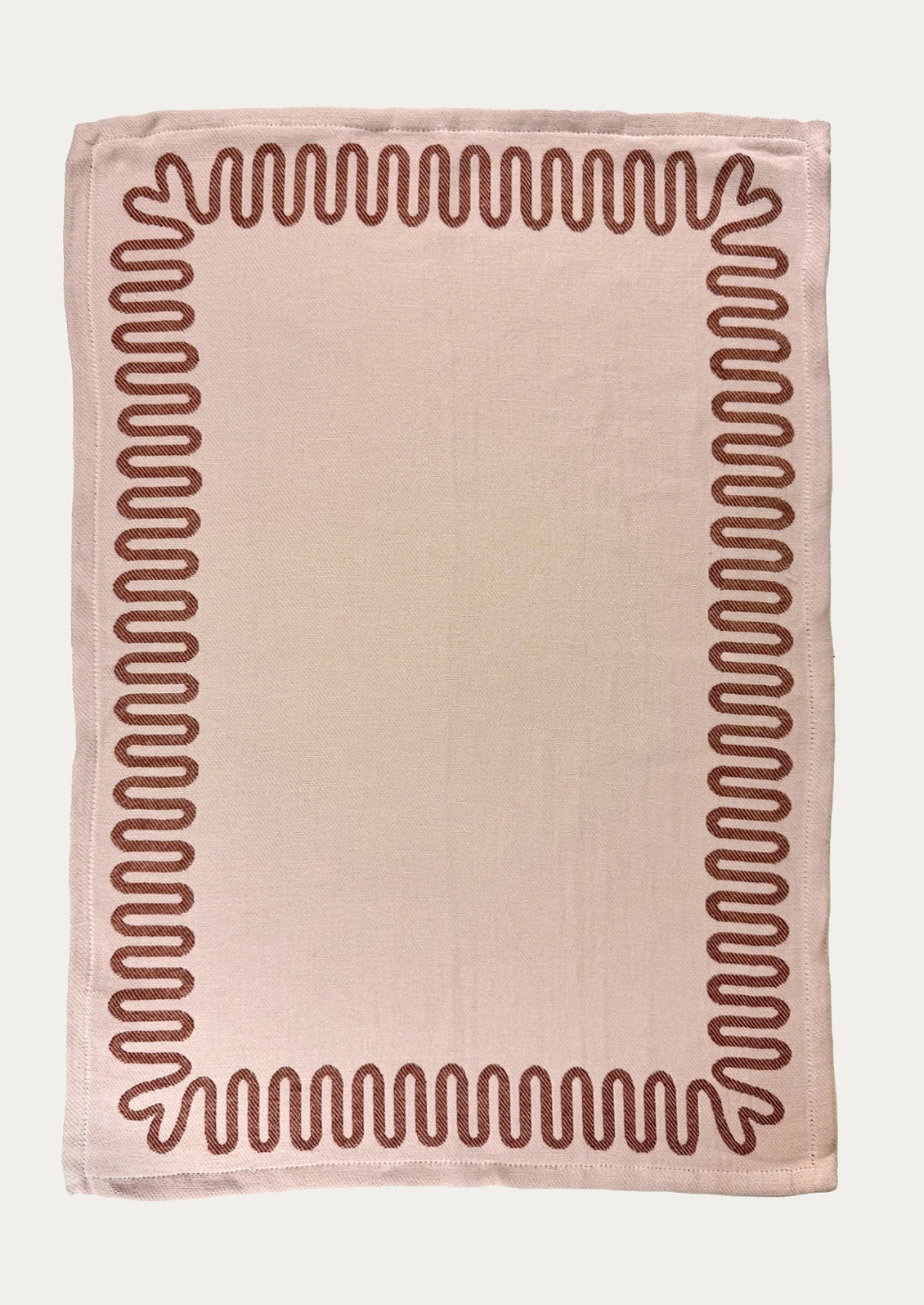 A pink dish towel with red squiggle border.