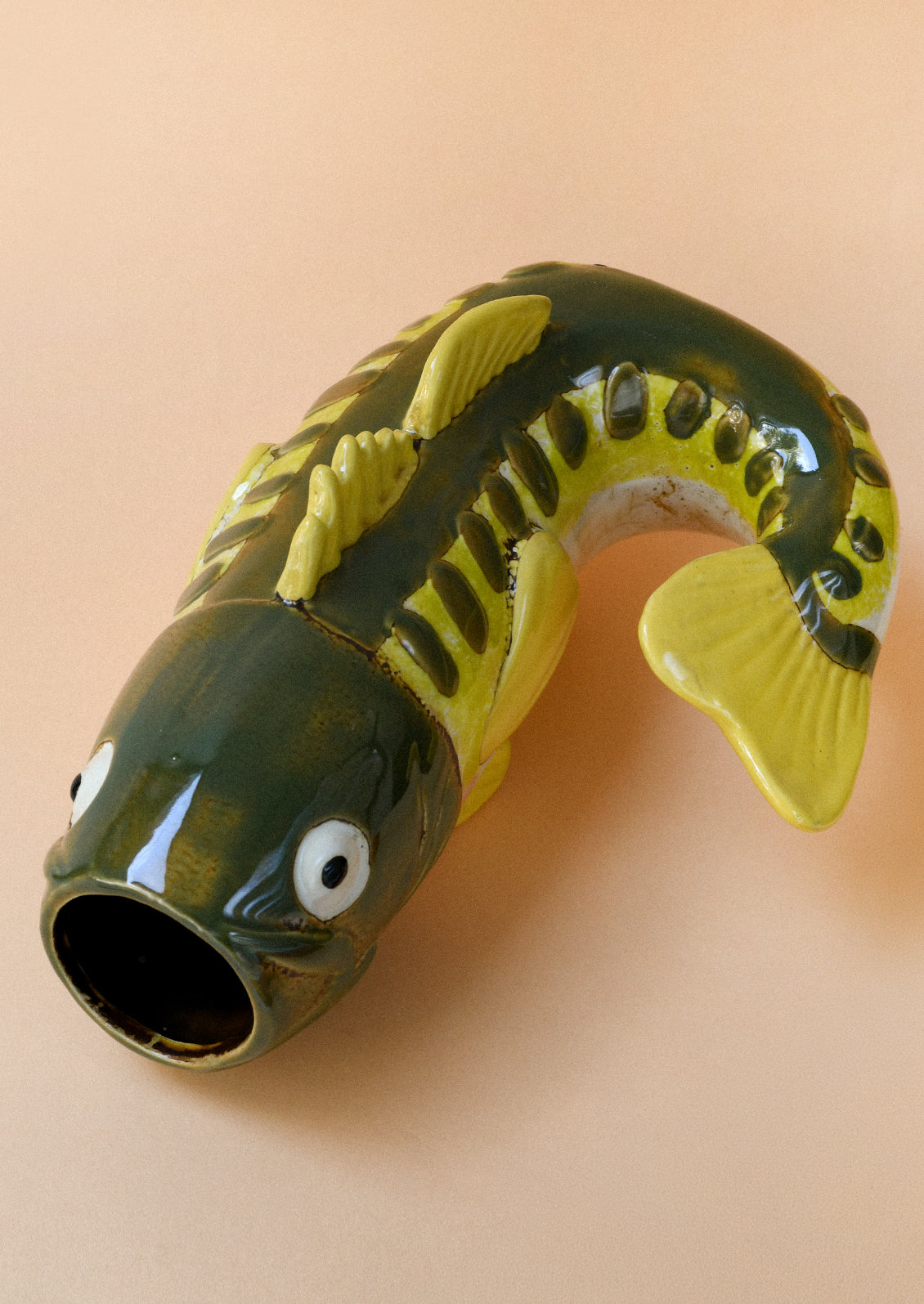 A ceramic vase in the shape of a green and yellow trout.
