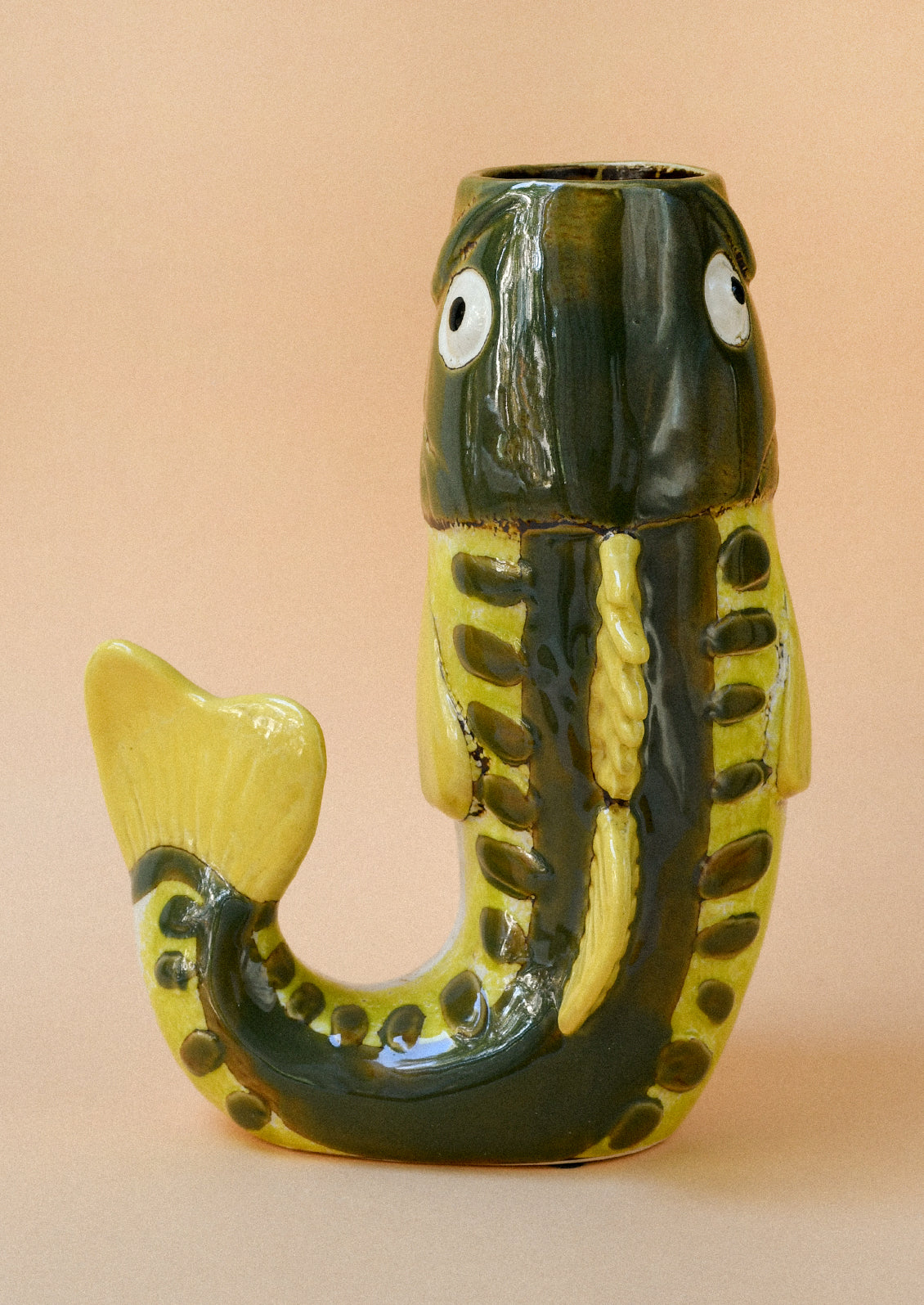 A ceramic vase in the shape of a green and yellow trout.