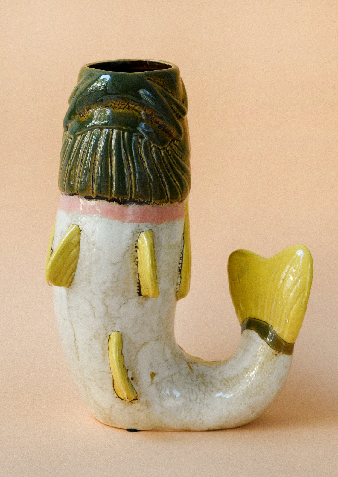 A ceramic vase in the shape of a green and yellow trout.