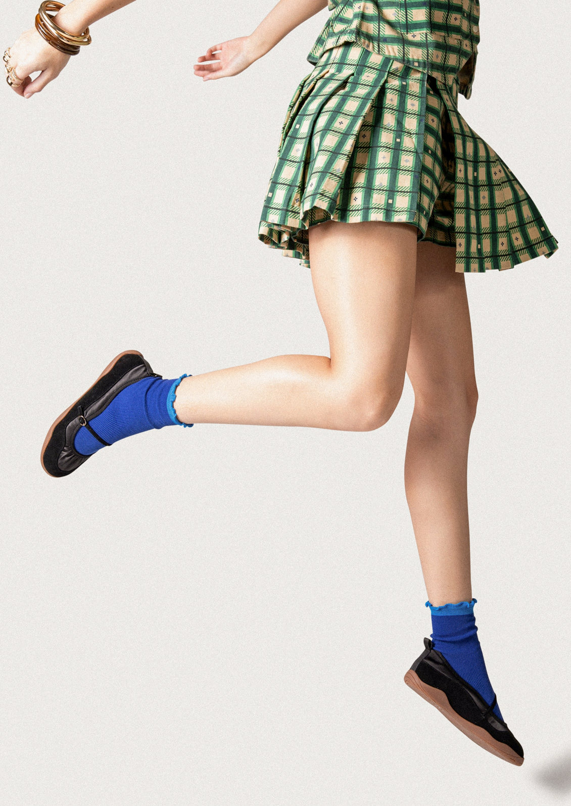 A woman wearing a pair of black shoes that are part sneaker, part ballet flat mary jane. Suede/textile upper with a rubber gum sole.