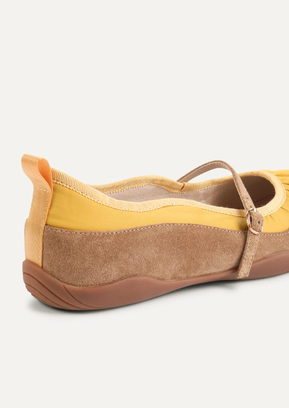 A yellow and taupe shoe that is part sneaker, part ballet flat mary jane. Suede/textile upper with a rubber gum sole.