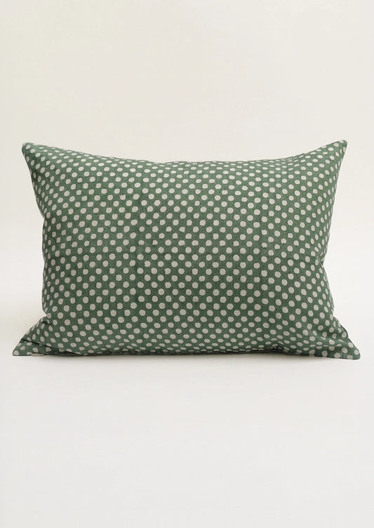A lumbar throw pillow in green with white polka dots.