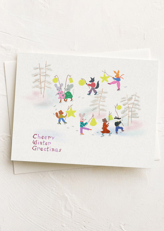 A greeting card with illustration of animals in a winter setting parade holding yellow lanterns.