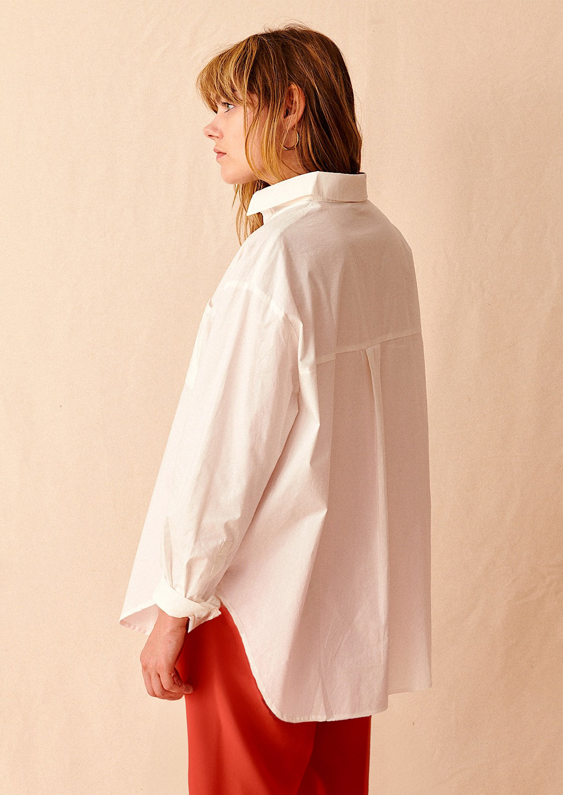 A woman wearing an oversized white cotton shirt.