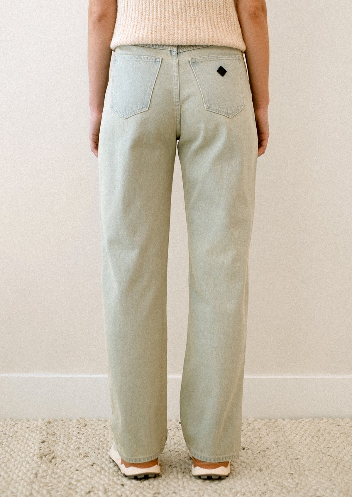 A woman wearing a pair of jeans in subtle green tinted light blue wash.
