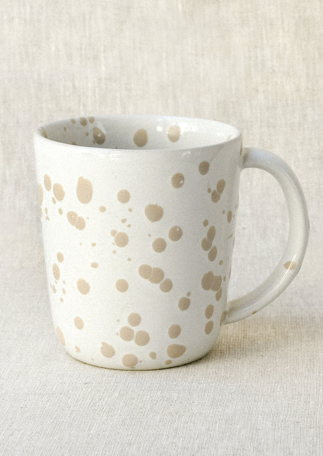A white mug with a brown paint splatter design.