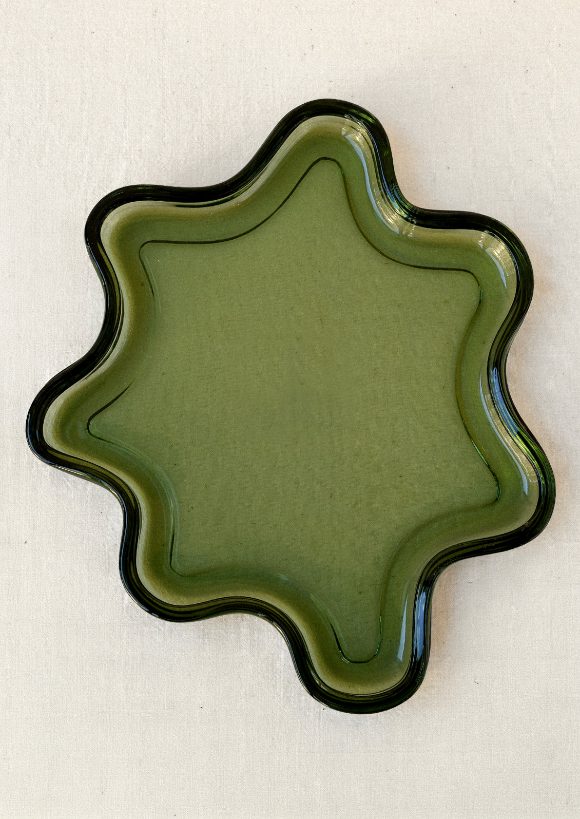 An olive green glass tray in a squiggle shape.