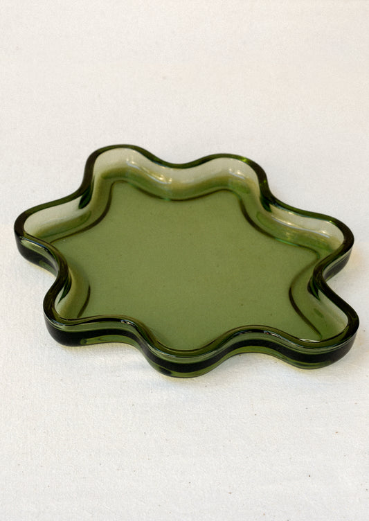 An olive green glass tray in a squiggle shape.