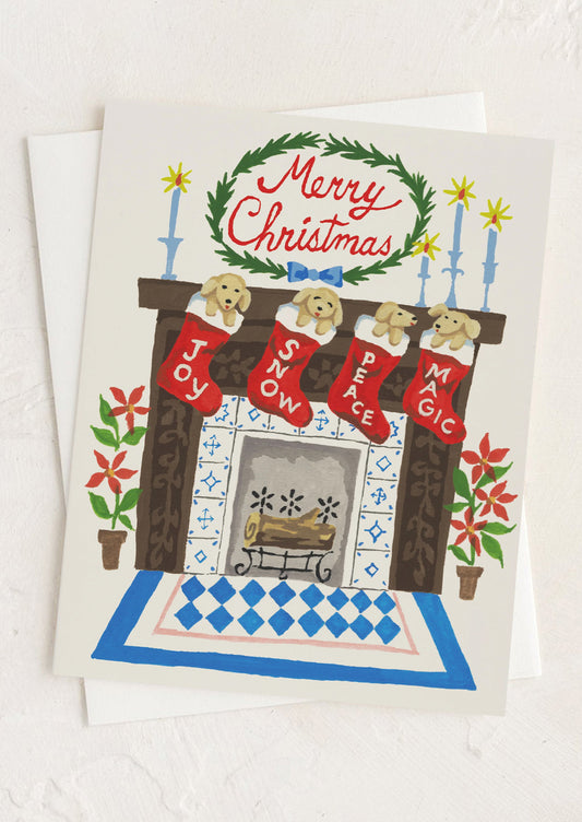 A greeting card with illustration of puppies in stockings by a fireplace, text at top reads "Merry Christmas".