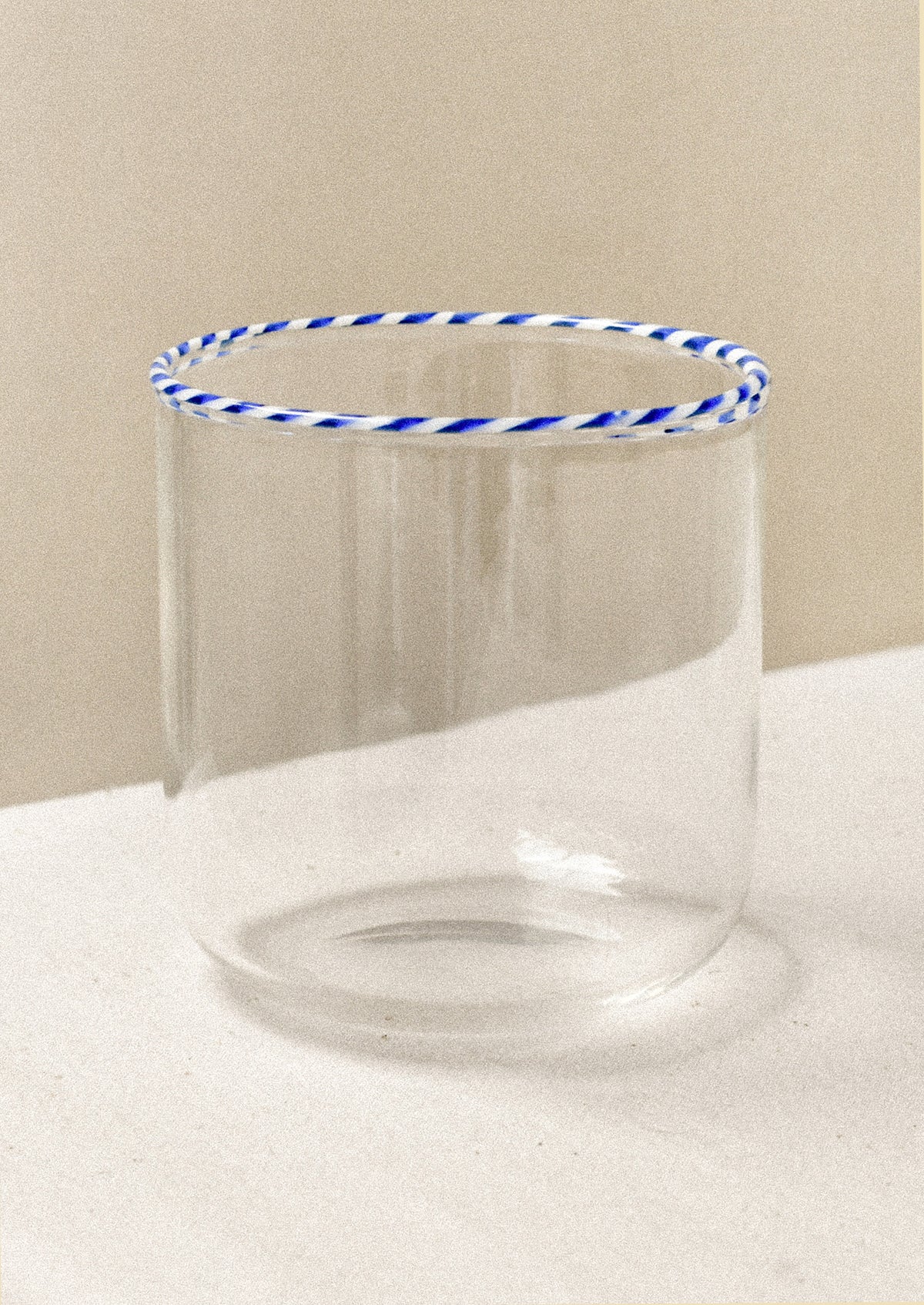A clear drinking glass with a blue striped rim