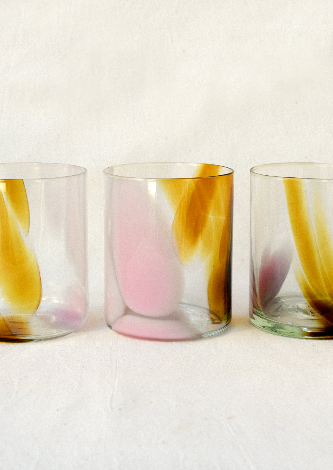 Clear glass tumblers with an abstract brown and pink design.