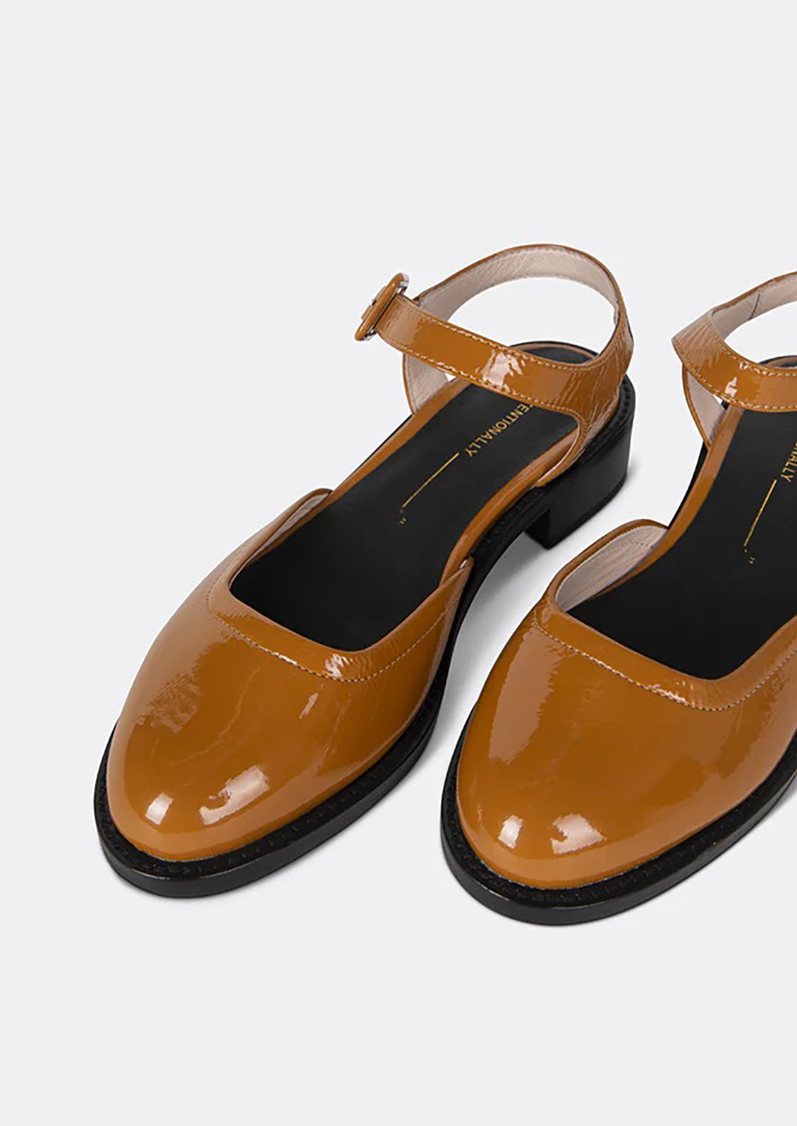 A pair of mary jane shoes with block heel in brown patent leather.