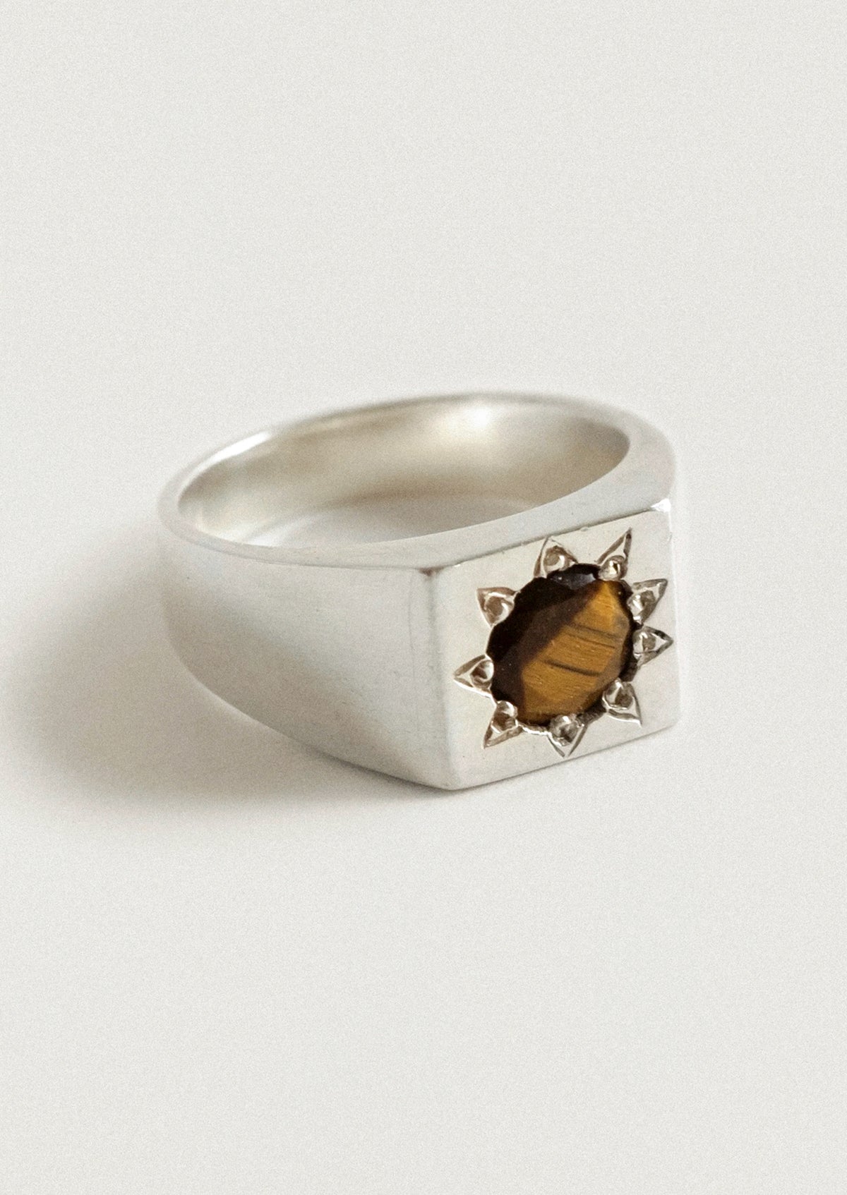 A chunky sterling silver ring with a starburst design and a brown gemstone in the center.