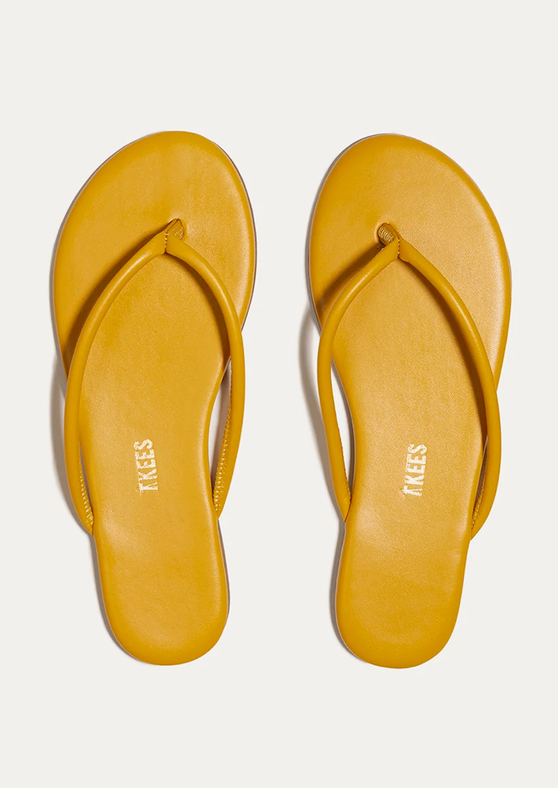 A pair of leather TKEES sandals with a tubular strap design in deep yellow.