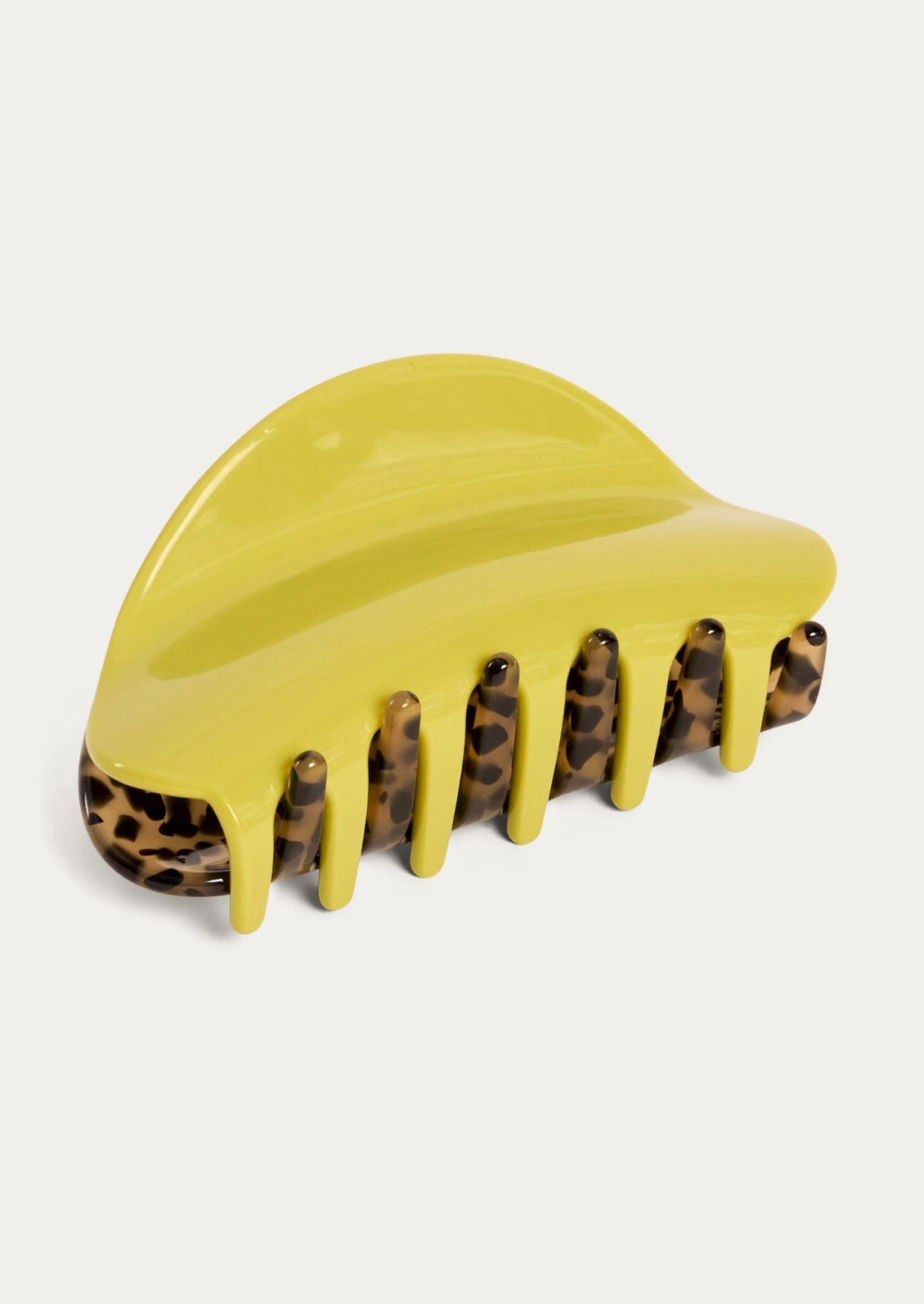 A two-tone hair claw with a chartreuse color on one side and a tortoise pattern on the other side.