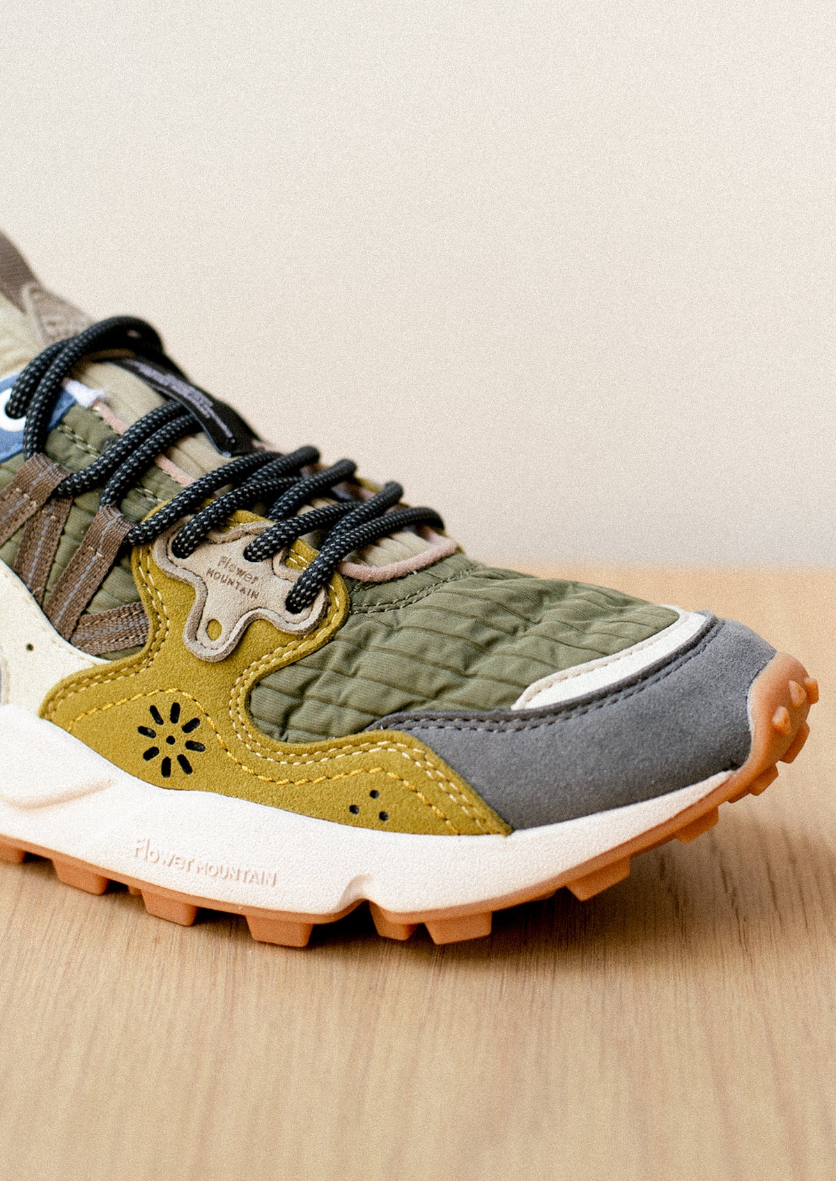 A pair of sneakers in ribbed nylon and suede, green and mustard color palette.