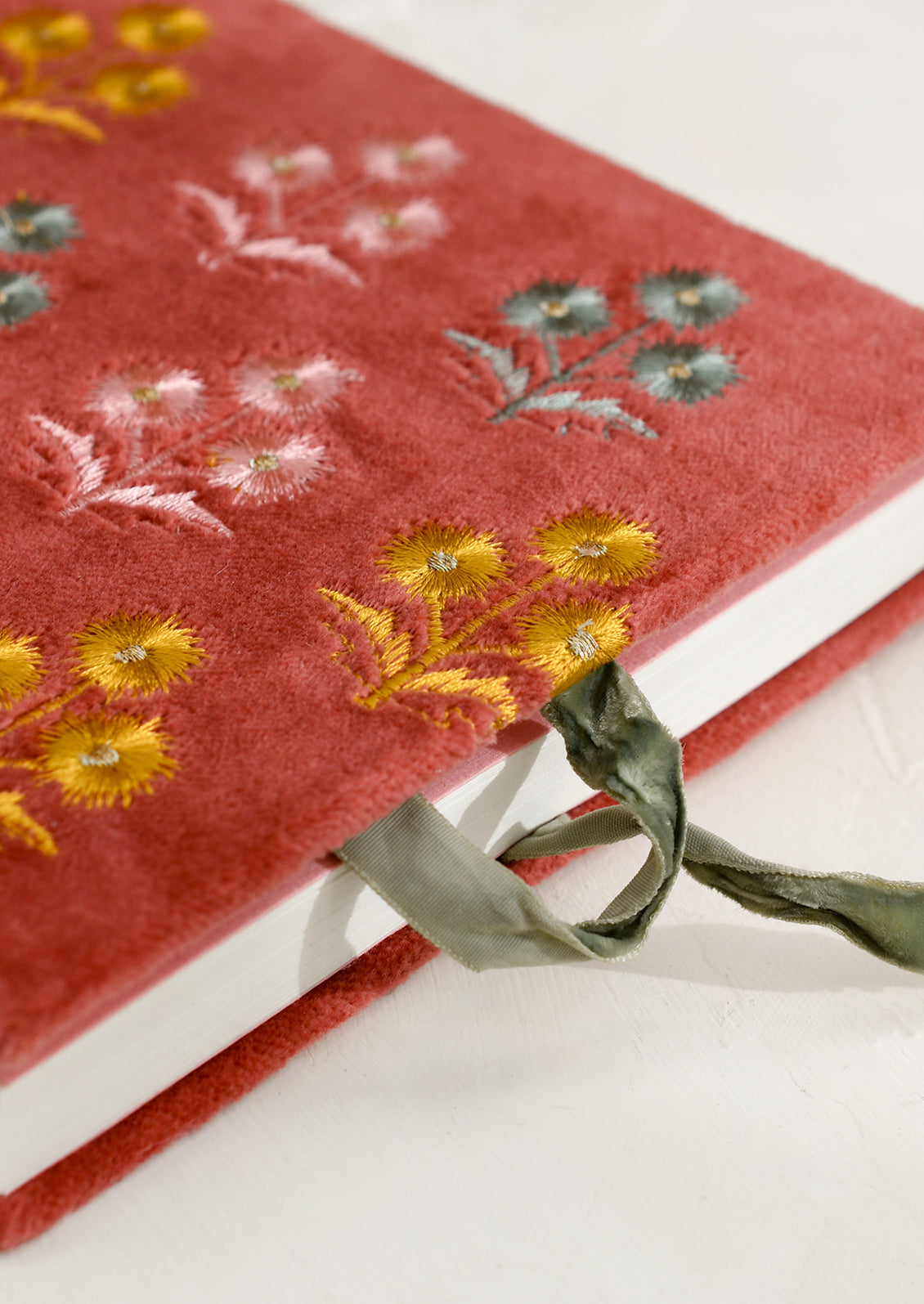 A rectangular journal in rust colored velvet with yellow, pink and mint floral embroidery.