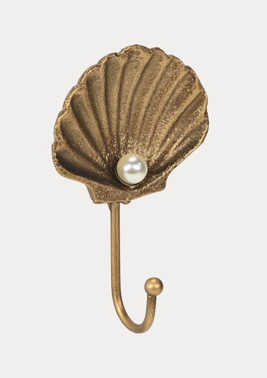 Side view of a handcrafted gold cast iron wall hook in the shape of a shell with a faux pearl in the center on a white background.