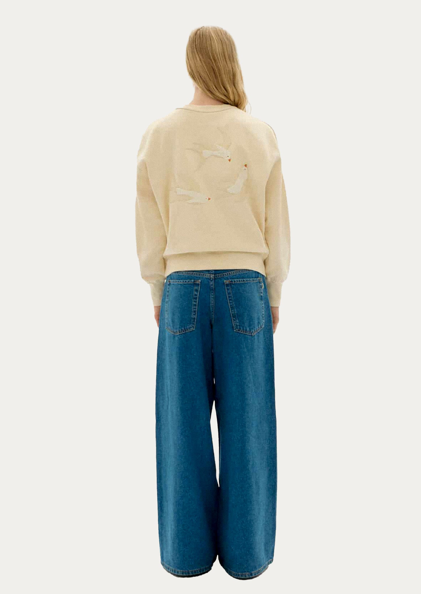 Beige sweatshirt with swallowtail bird applique detailing on back.
