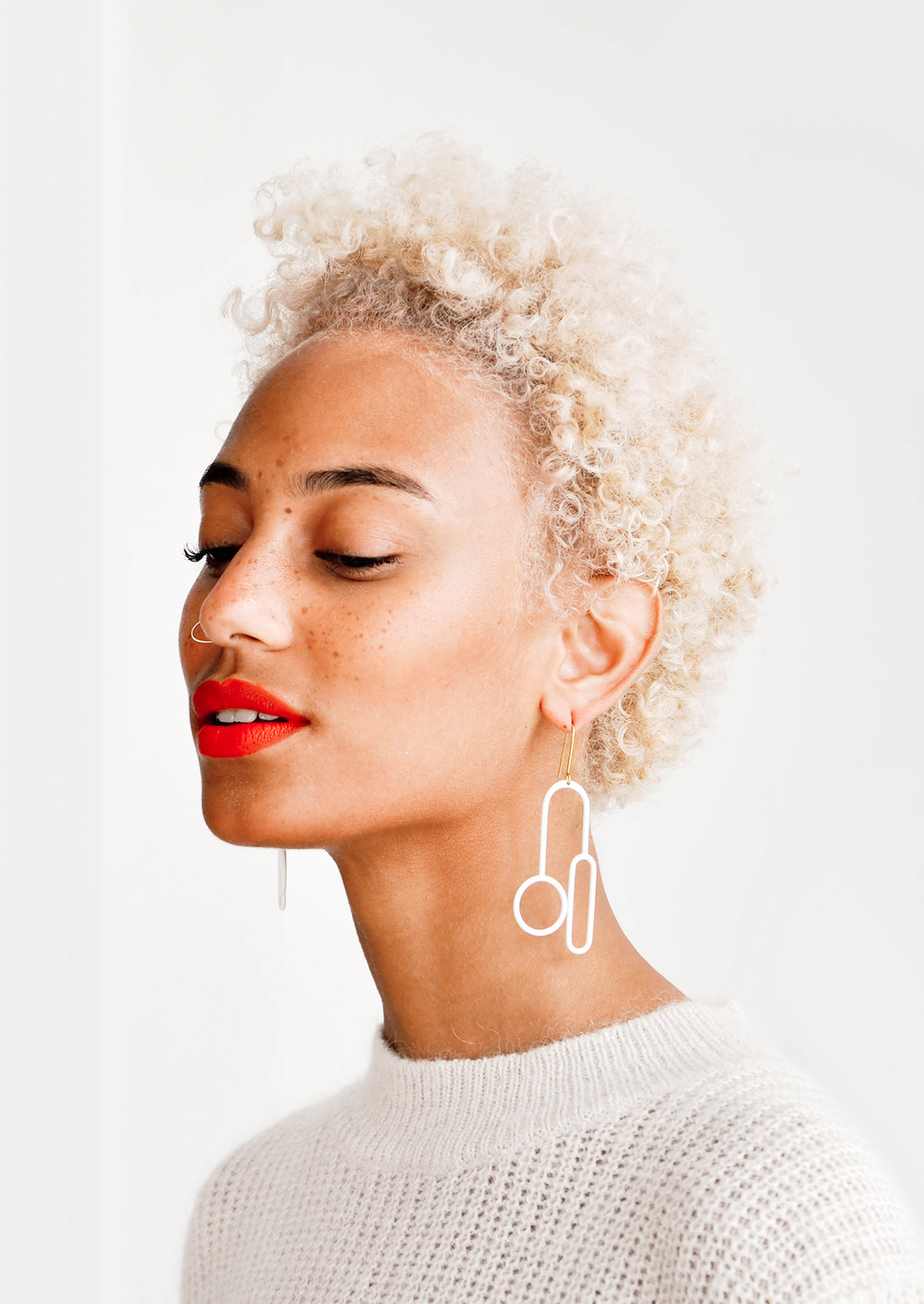Model wears white enamel mixed shape earrings.