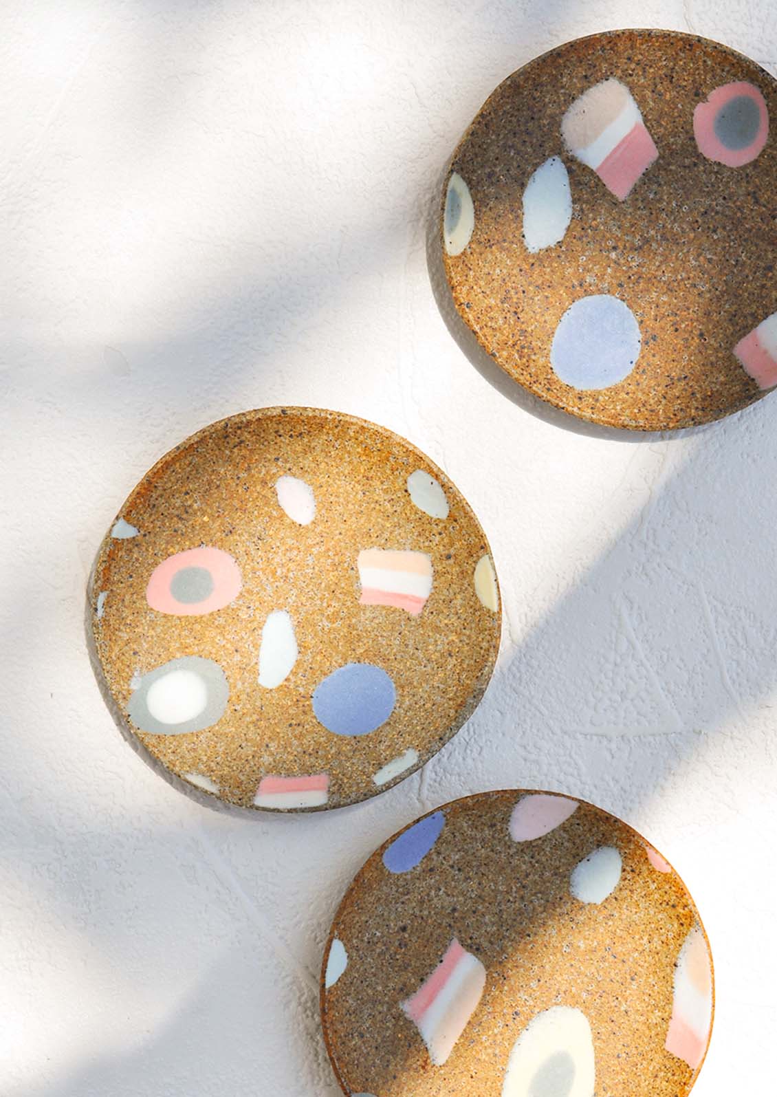 Scattered ceramic trinket dishes with various inlay shapes.