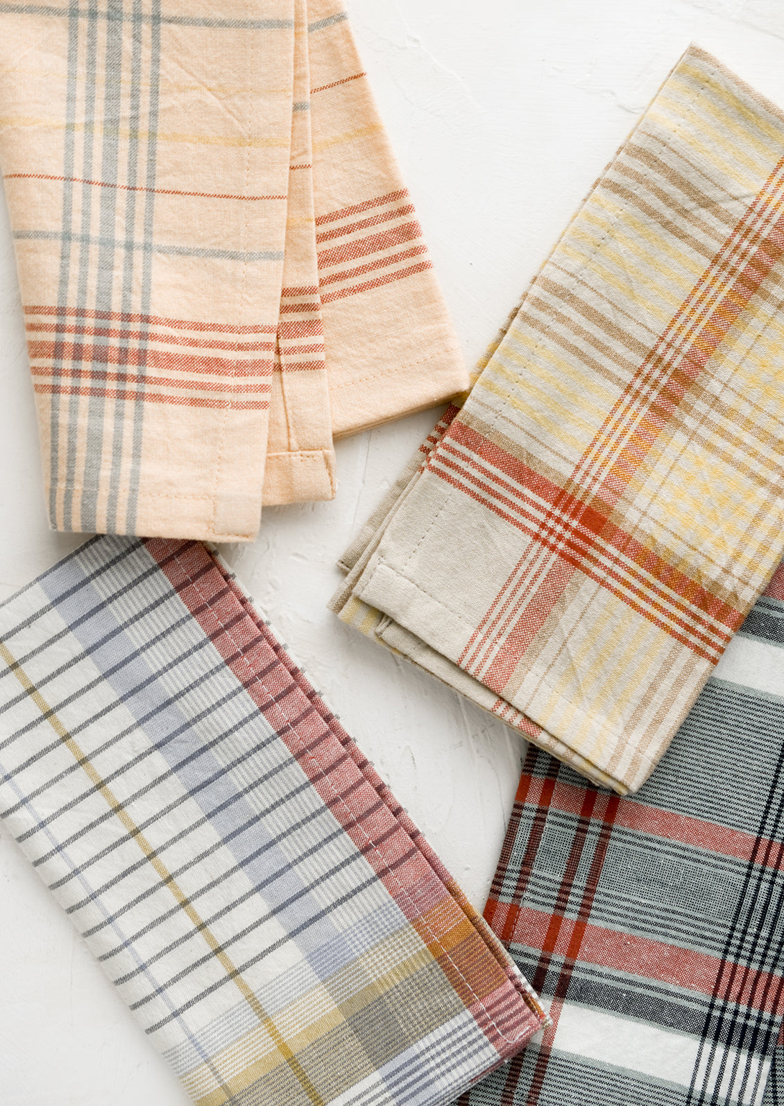 A set of four napkins in plaid pattern and assorted colors.