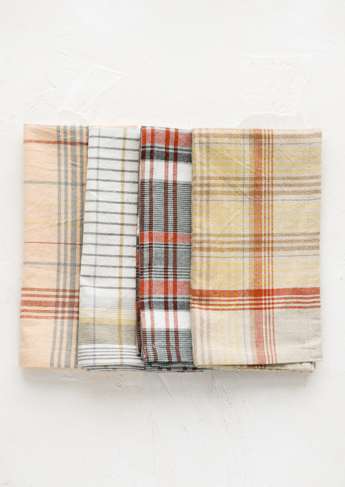 A set of four napkins in plaid pattern and assorted colors.