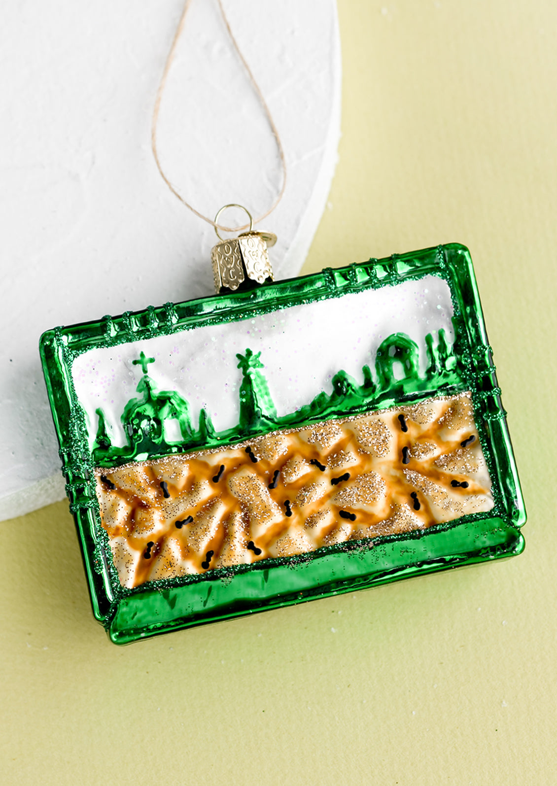 A glass ornament of a green ant farm.